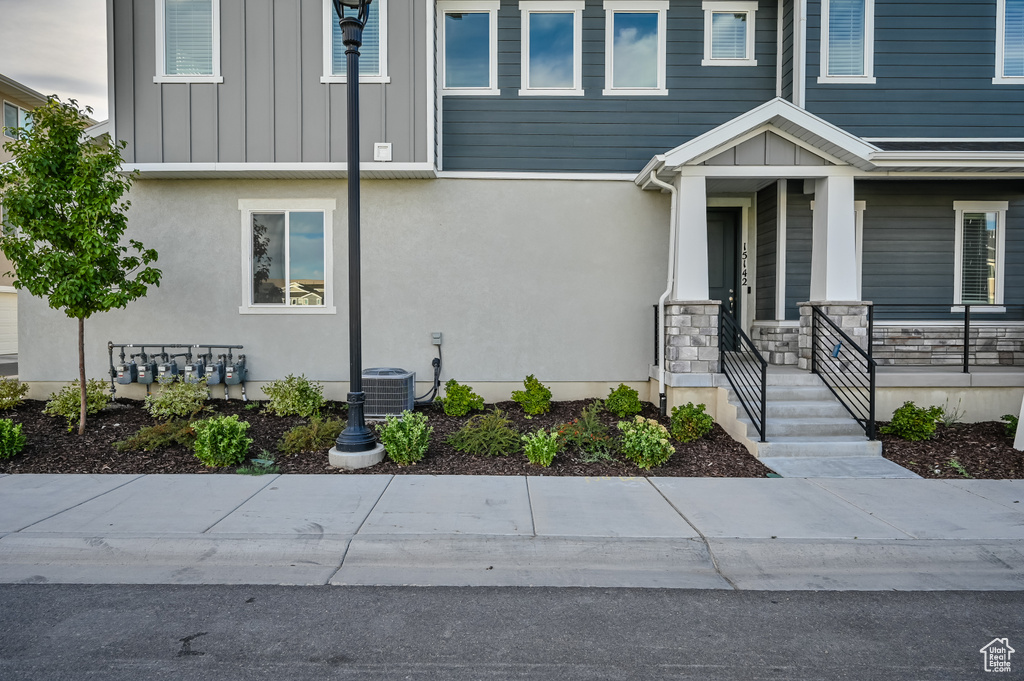 View of front of house featuring a porch, board and batten siding, stucco siding, and stone siding
