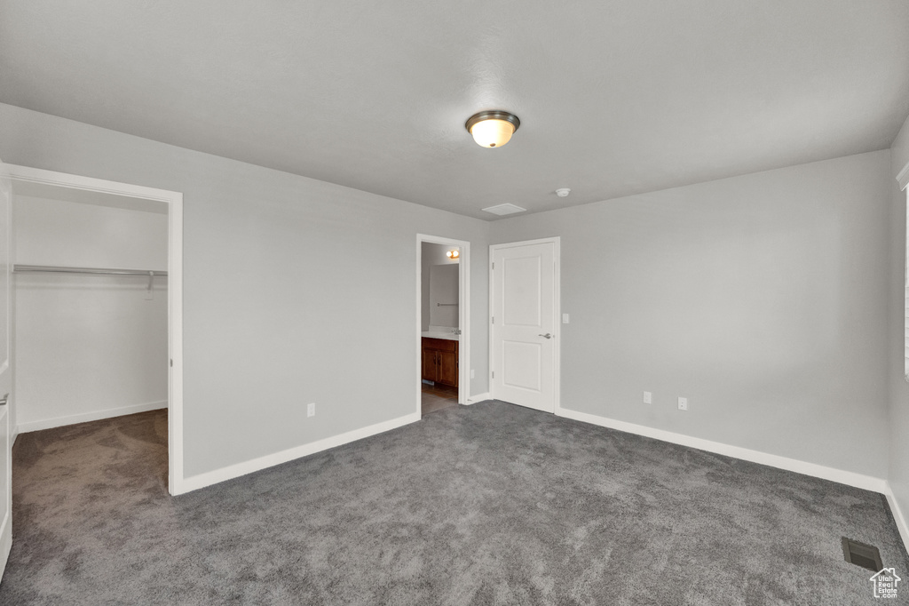 Unfurnished bedroom featuring carpet, a walk in closet, and a closet