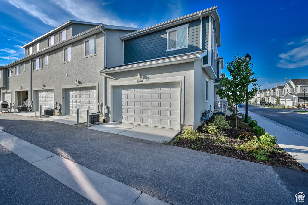 View of side of property with stucco siding, a residential view, and an attached garage