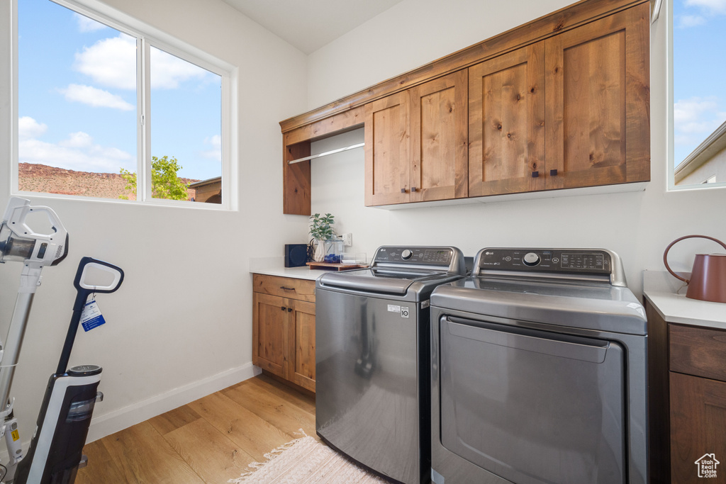 Laundry room featuring cabinet space, light wood-style floors, and washing machine and clothes dryer