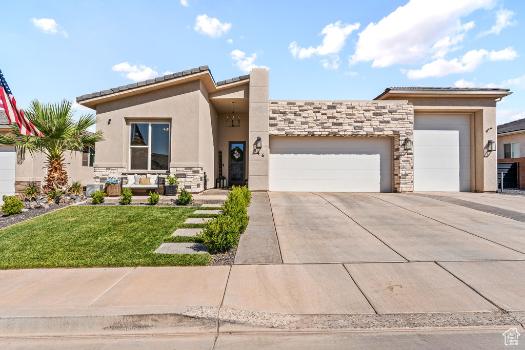 View of front facade with stone siding, stucco siding, an attached garage, and concrete driveway
