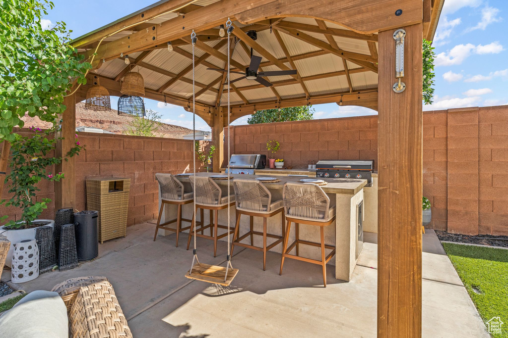 Fenced backyard featuring a gazebo, exterior kitchen, ceiling fan, and a patio area