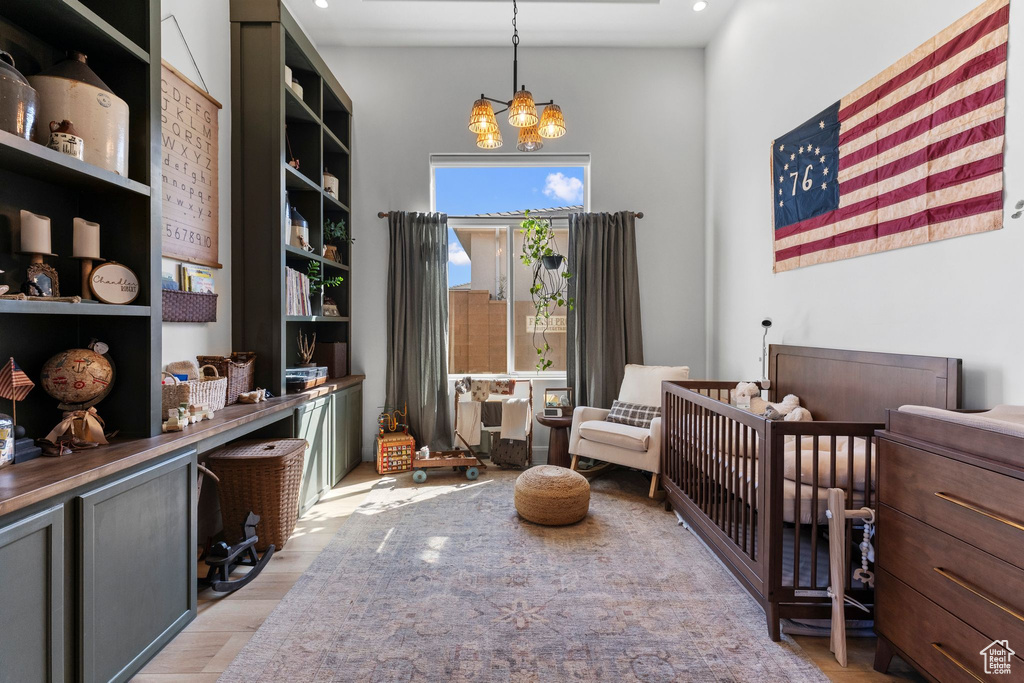 Bedroom featuring a chandelier, light wood finished floors, a crib, recessed lighting, and a high ceiling