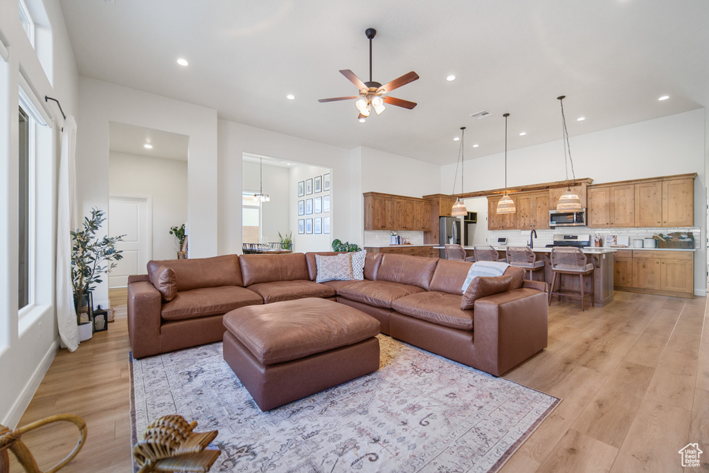 Living area with recessed lighting, a ceiling fan, light wood-style flooring, and a towering ceiling