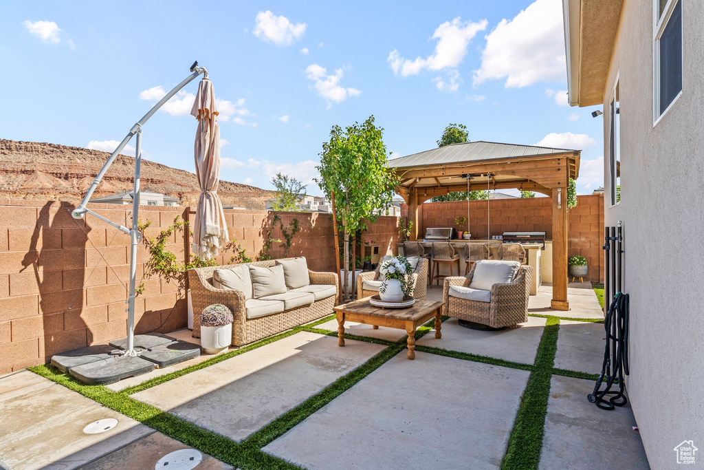Fenced backyard with an outdoor hangout area, a patio area, a gazebo, and an outdoor kitchen