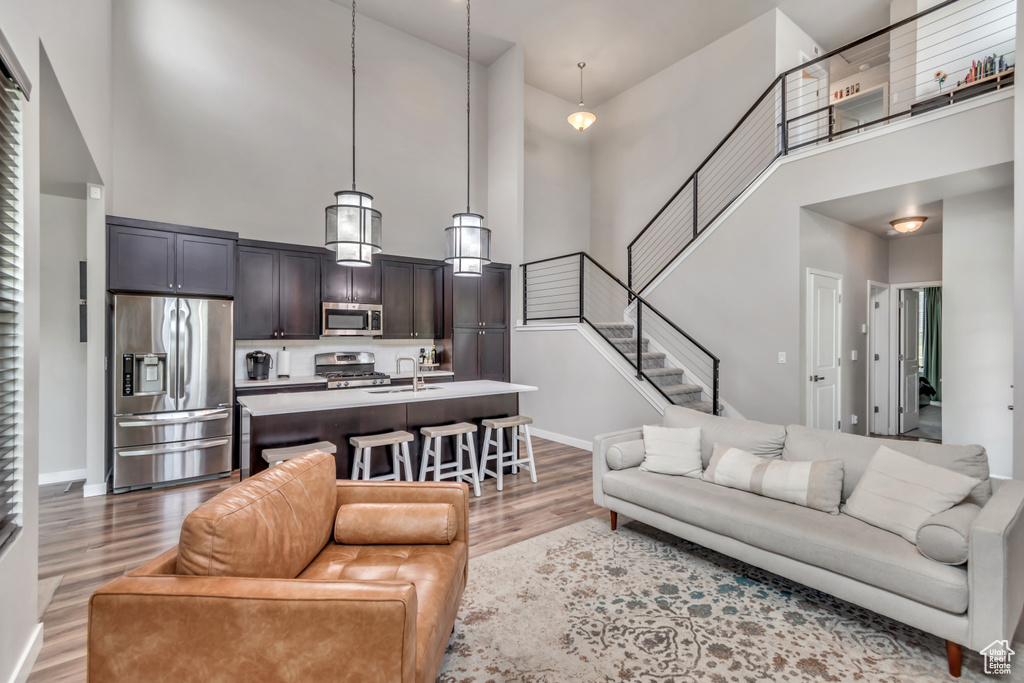 Living area featuring a towering ceiling, wood finished floors, and stairs