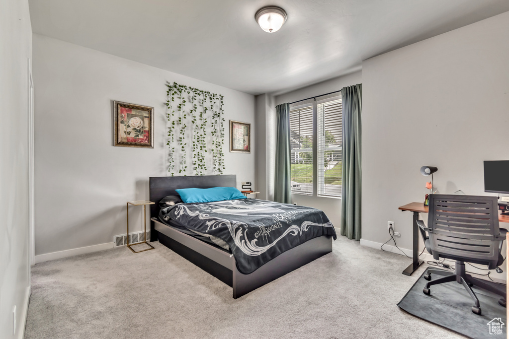 Carpeted bedroom featuring baseboards and an office area