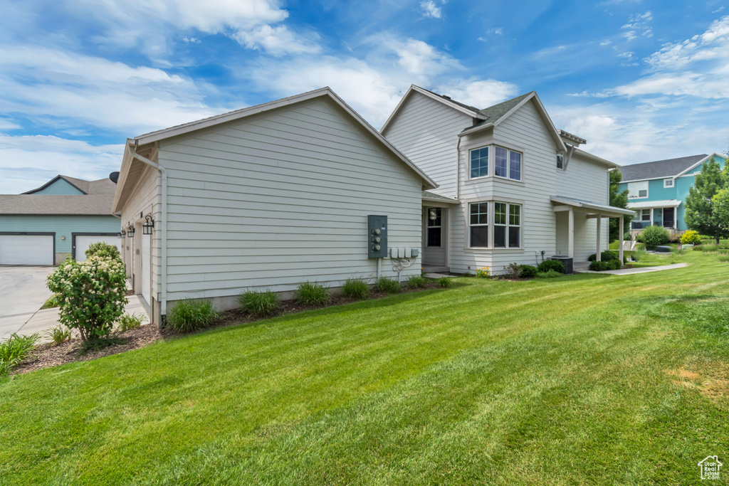 Rear view of property featuring a lawn, driveway, and an attached garage