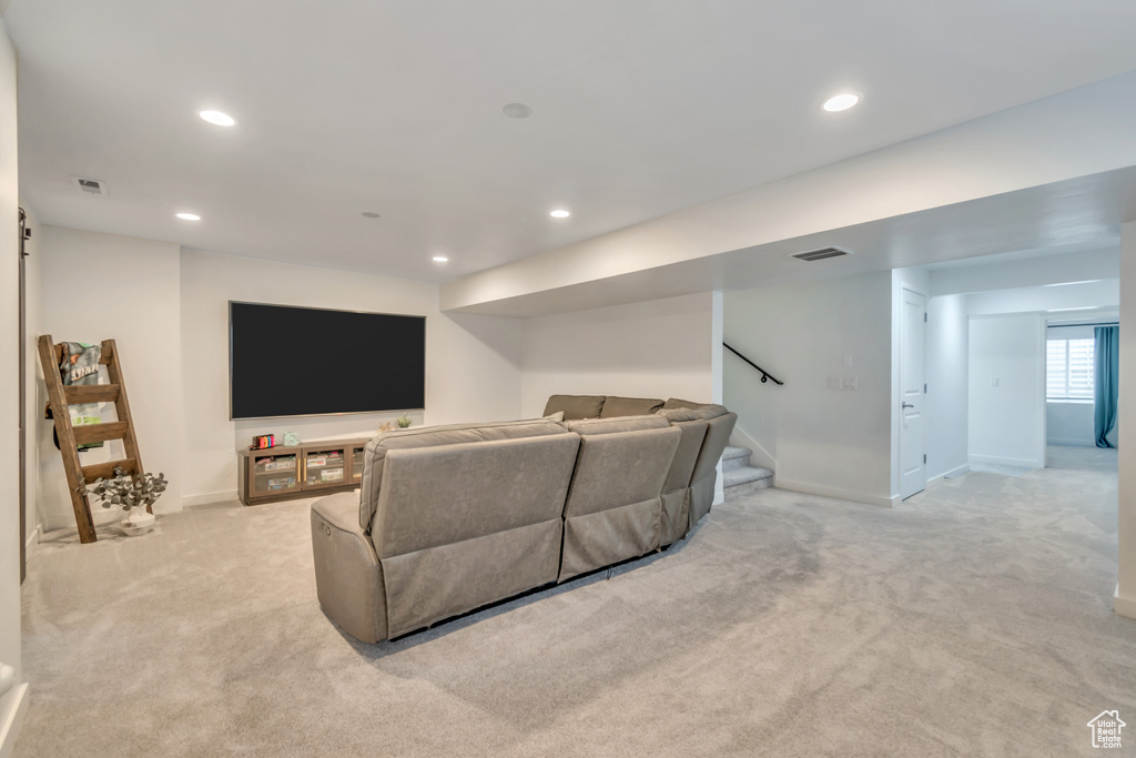 Living room with light colored carpet, recessed lighting, and stairway