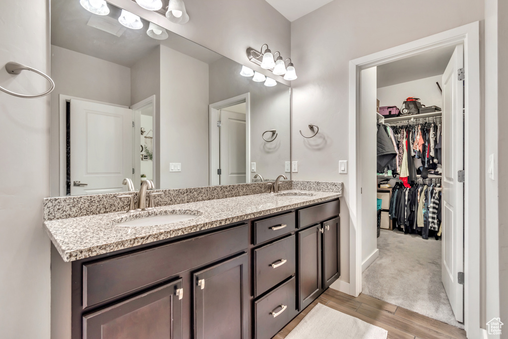Bathroom with double vanity, wood finished floors, and a spacious closet