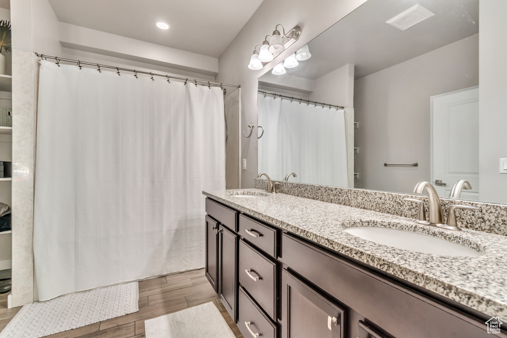 Bathroom featuring wood finished floors, double vanity, recessed lighting, and curtained shower