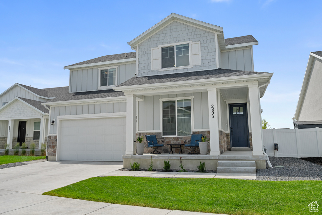 Craftsman-style house with board and batten siding, a porch, a garage, driveway, and a shingled roof