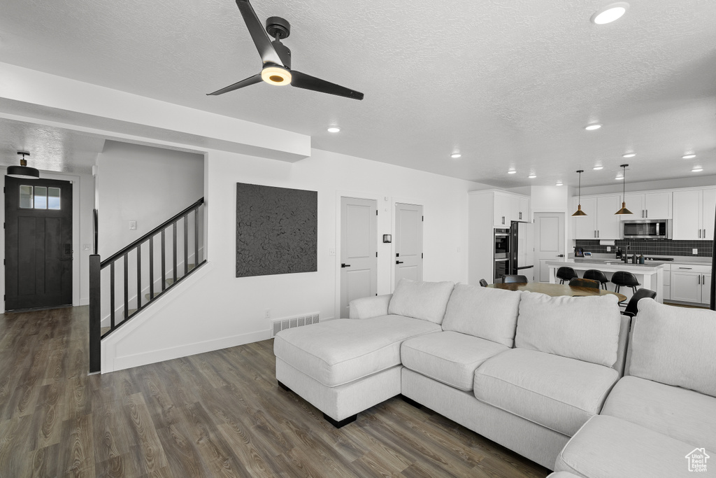 Living area featuring a ceiling fan, dark wood finished floors, recessed lighting, a textured ceiling, and stairs