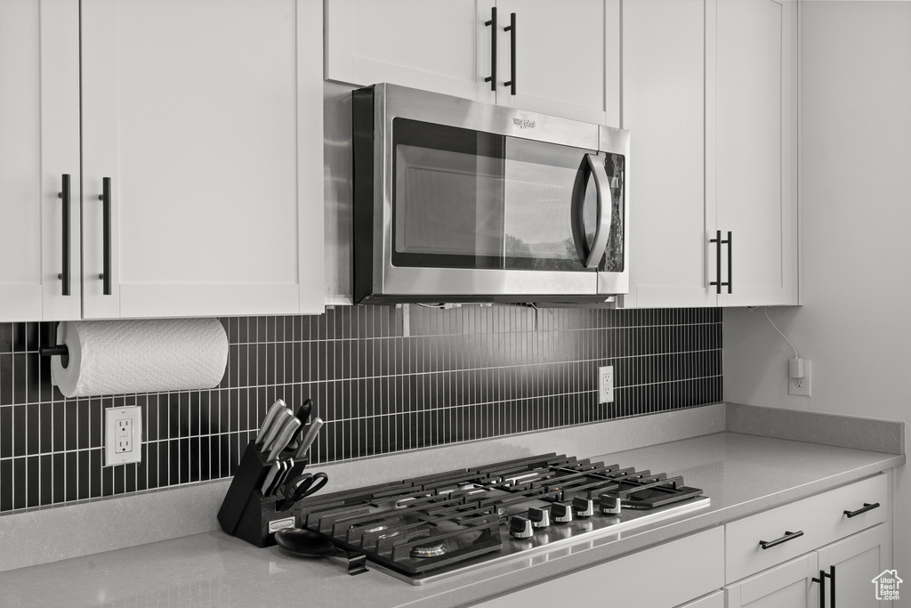 Kitchen featuring appliances with stainless steel finishes, white cabinetry, and tasteful backsplash