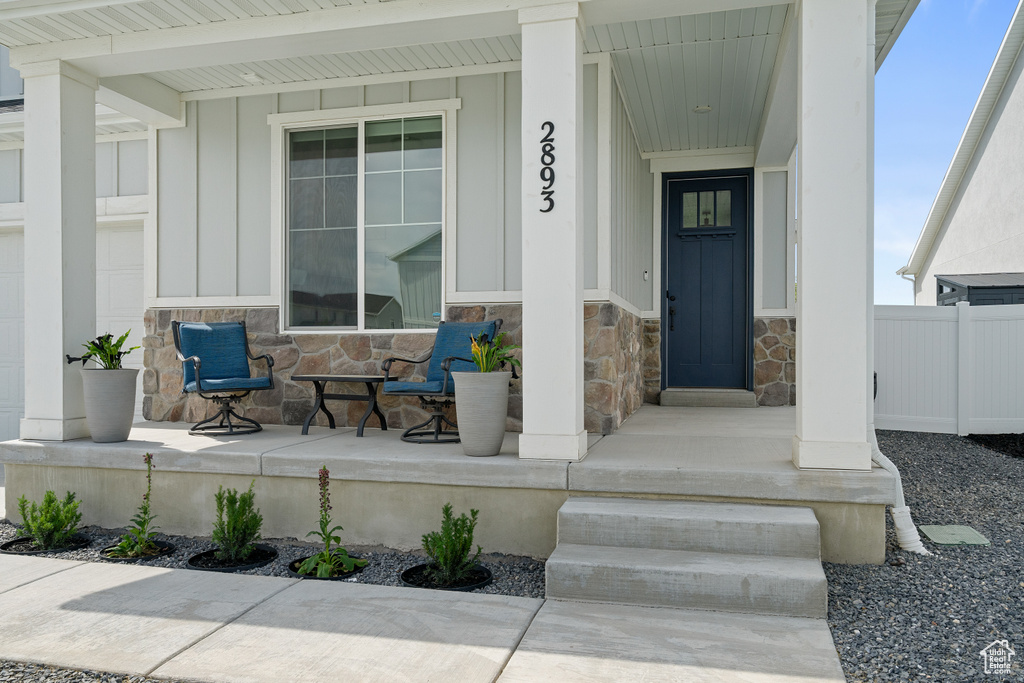Entrance to property featuring stone siding, covered porch, and board and batten siding