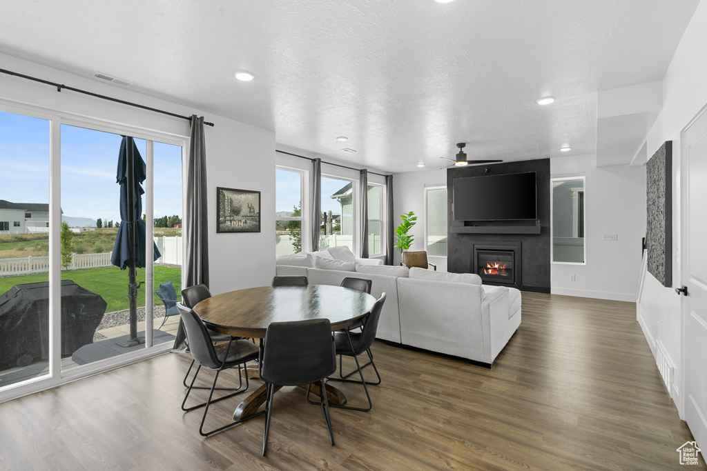 Dining area featuring a ceiling fan, a large fireplace, dark wood-type flooring, and recessed lighting