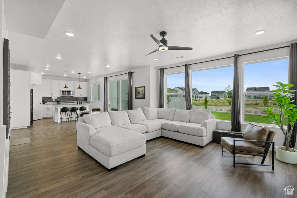 Living room featuring a ceiling fan, dark wood finished floors, recessed lighting, and a textured ceiling