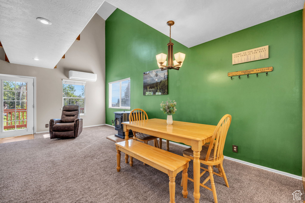 Dining area featuring a chandelier, carpet floors, a wall unit AC, lofted ceiling, and a textured ceiling