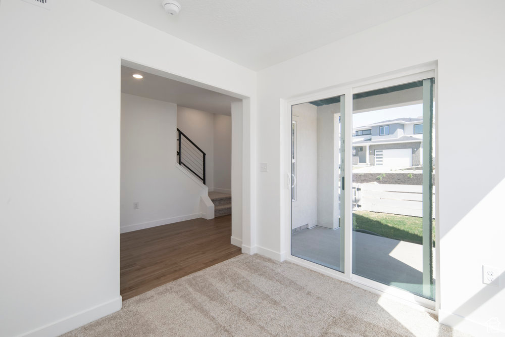 Unfurnished room featuring carpet flooring, a smoke detector, and stairway