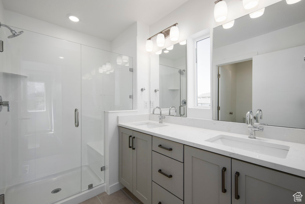 Bathroom featuring a stall shower, double vanity, tile patterned flooring, and recessed lighting