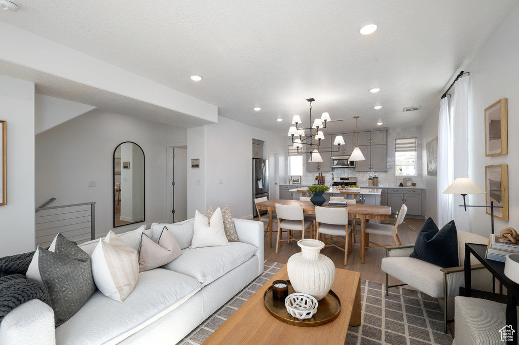 Living room featuring dark wood-style flooring, a chandelier, and recessed lighting