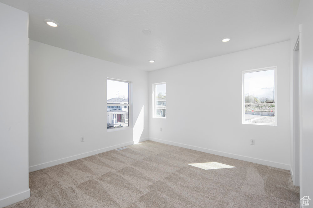 Spare room featuring light colored carpet and recessed lighting