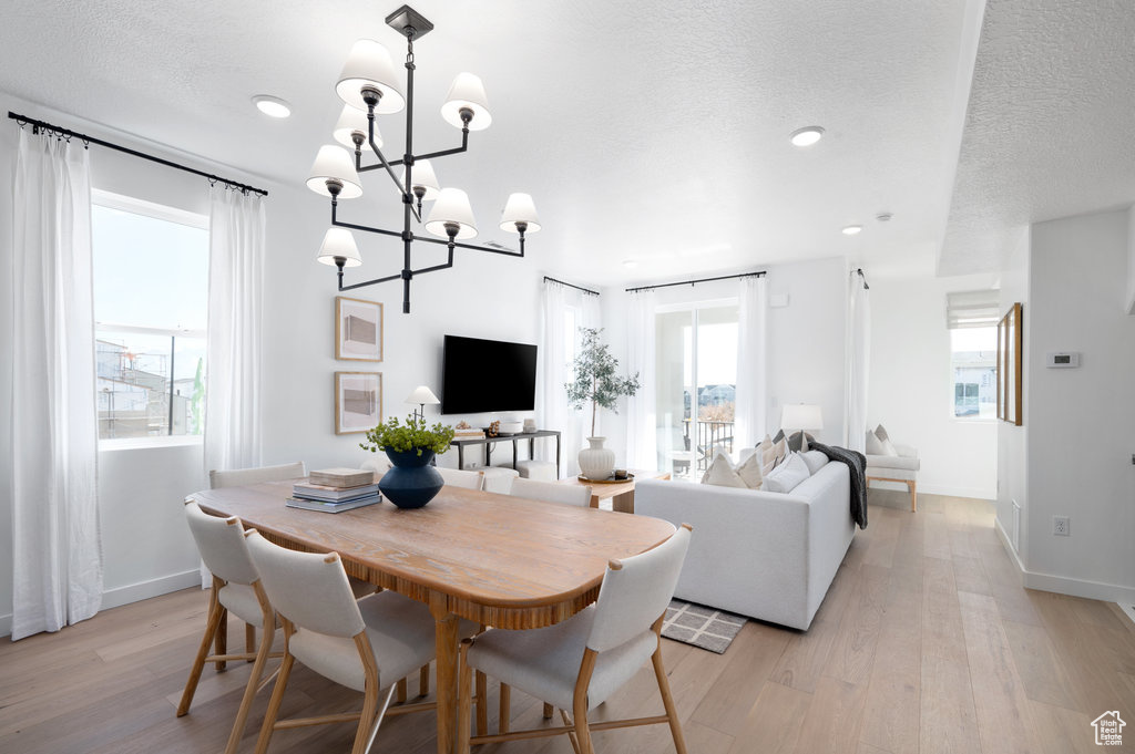 Dining room featuring light wood-style flooring, a chandelier, a textured ceiling, and recessed lighting