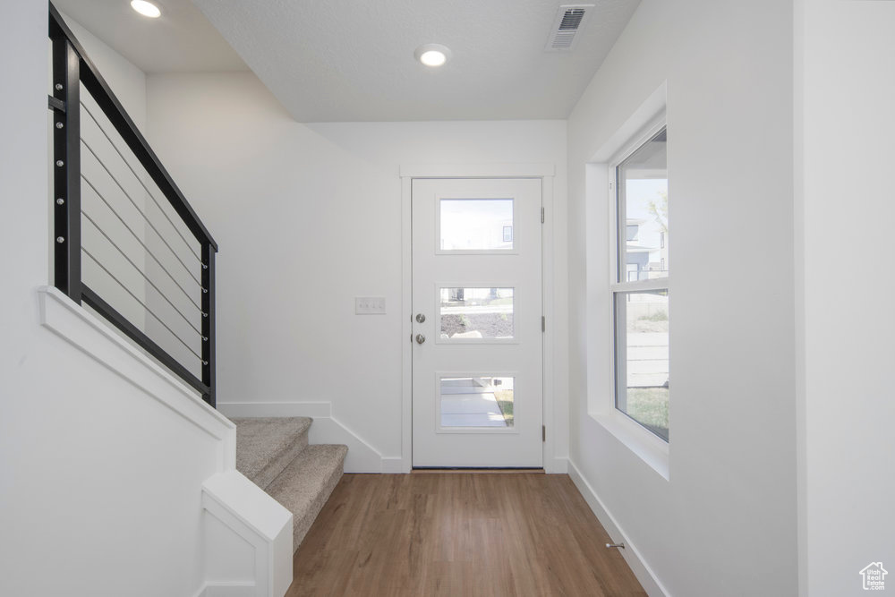 Foyer featuring stairs, wood finished floors, and recessed lighting
