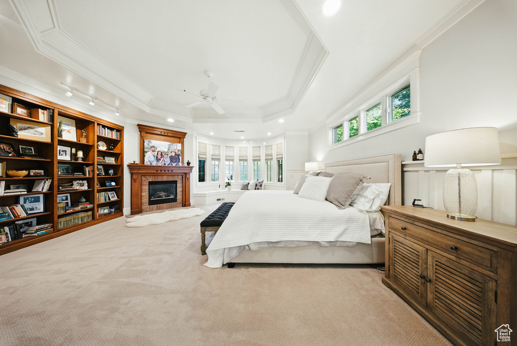 Bedroom featuring crown molding, a tiled fireplace, carpet, a raised ceiling, and recessed lighting