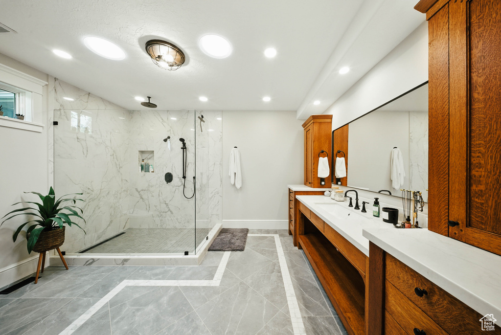 Bathroom featuring marble finish flooring, a marble finish shower, recessed lighting, and vanity