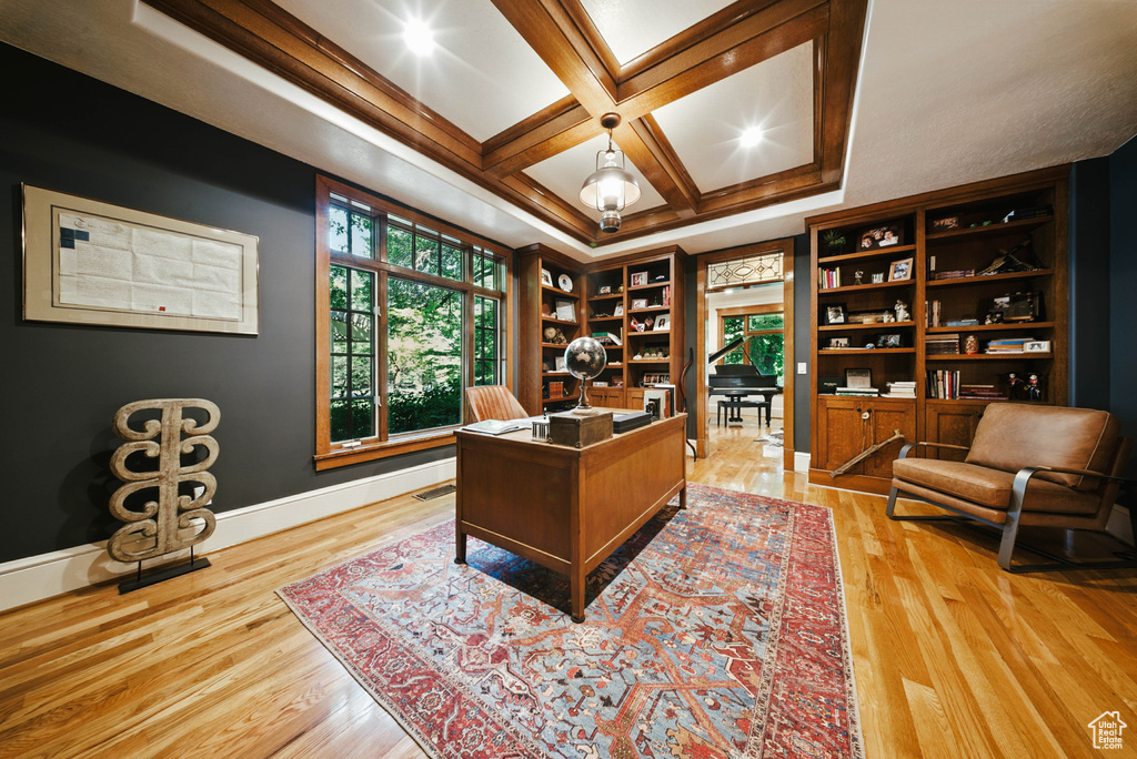 Office space featuring light wood finished floors, coffered ceiling, and beam ceiling