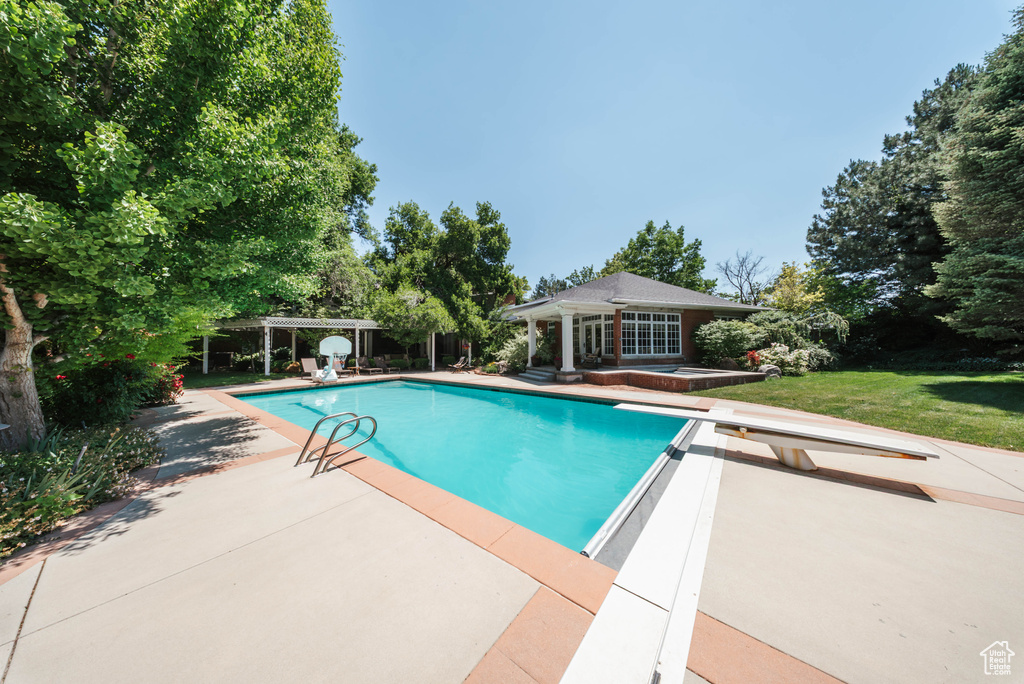 Swimming pool with a diving board, an exterior structure, a patio, and an outbuilding