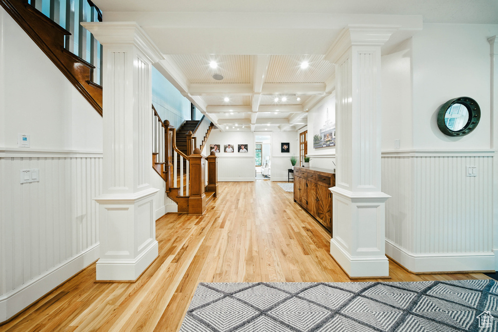 Corridor featuring decorative columns, beam ceiling, light wood finished floors, stairs, and recessed lighting