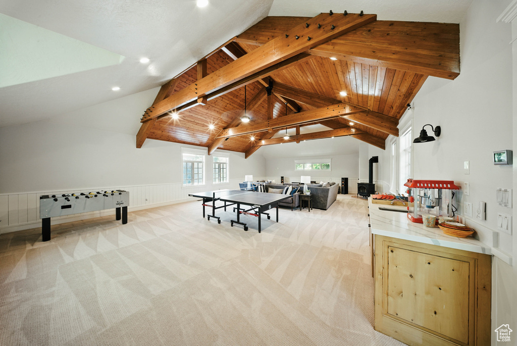 Rec room with beamed ceiling, light carpet, a wainscoted wall, recessed lighting, and high vaulted ceiling