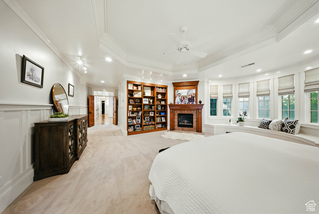 Bedroom with a tile fireplace, crown molding, recessed lighting, light colored carpet, and a decorative wall