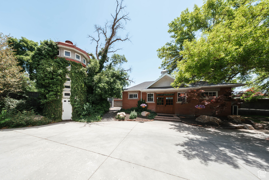View of front facade featuring brick siding, french doors, and driveway
