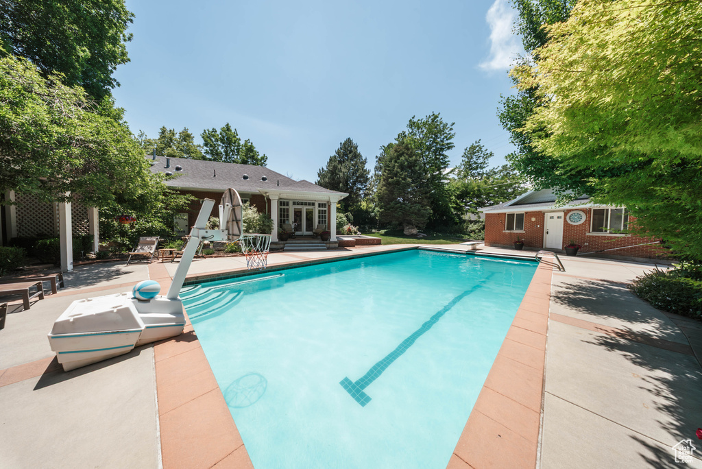 Outdoor pool featuring a patio, an outdoor structure, a diving board, and an exterior structure