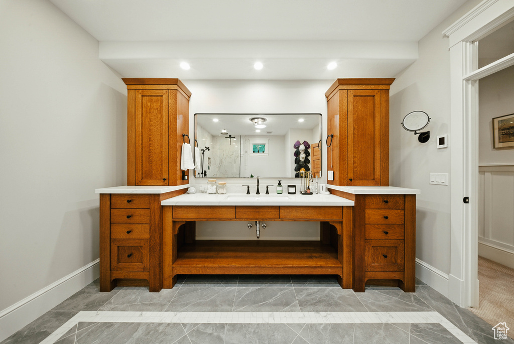 Bathroom featuring vanity, marble look tiles, recessed lighting, and a shower