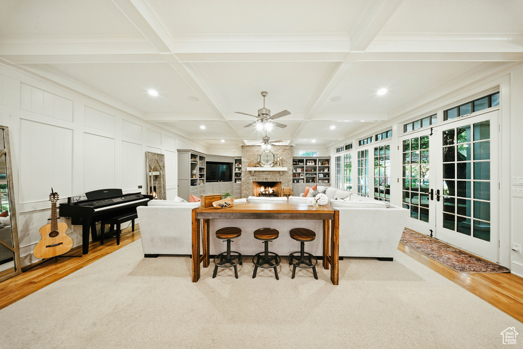 Kitchen featuring coffered ceiling, light wood-type flooring, a fireplace, a ceiling fan, and a kitchen bar