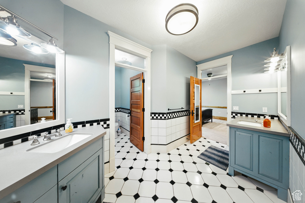 Bathroom featuring vanity, tile patterned floors, tile walls, and wainscoting