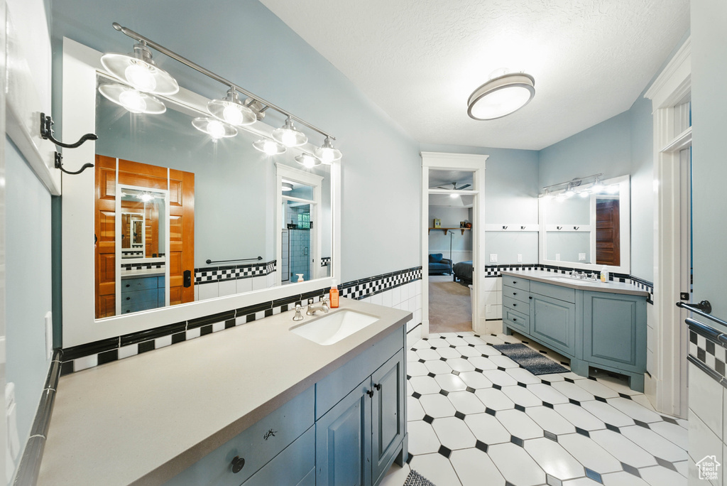 Full bathroom featuring two vanities, tile walls, and tile patterned floors