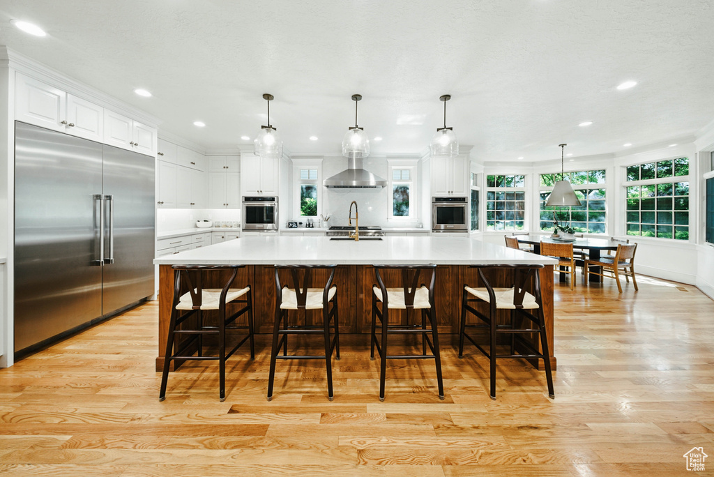 Kitchen with stainless steel built in fridge, light wood finished floors, white cabinetry, recessed lighting, and light countertops
