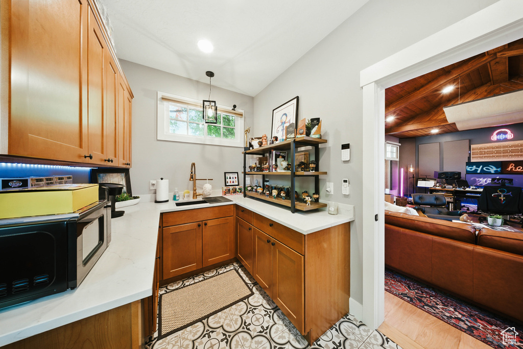 Kitchen with open floor plan, brown cabinets, black microwave, pendant lighting, and open shelves