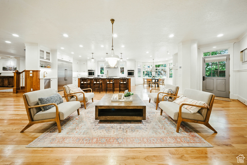 Living room featuring recessed lighting, light wood-type flooring, and ornamental molding