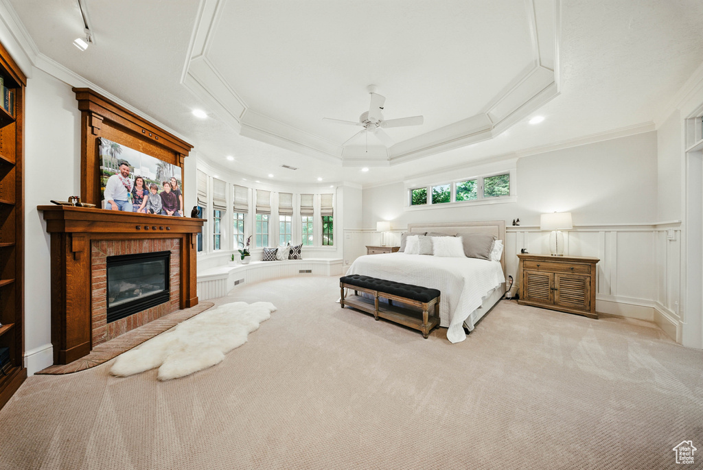 Carpeted bedroom with crown molding, a glass covered fireplace, recessed lighting, a wainscoted wall, and a decorative wall