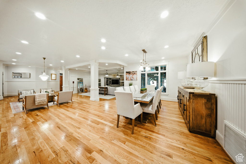 Dining room featuring ornate columns, recessed lighting, light wood-style flooring, and ornamental molding