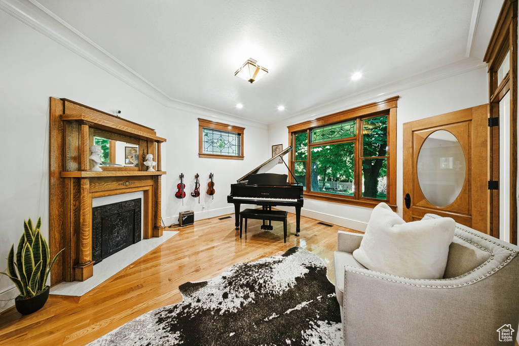 Living room featuring ornamental molding, wood finished floors, a fireplace with flush hearth, and recessed lighting