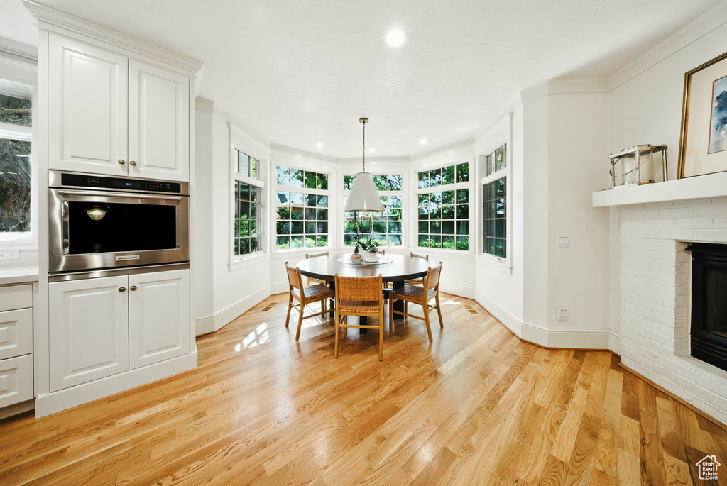 Dining area with light wood-style floors, a brick fireplace, and recessed lighting