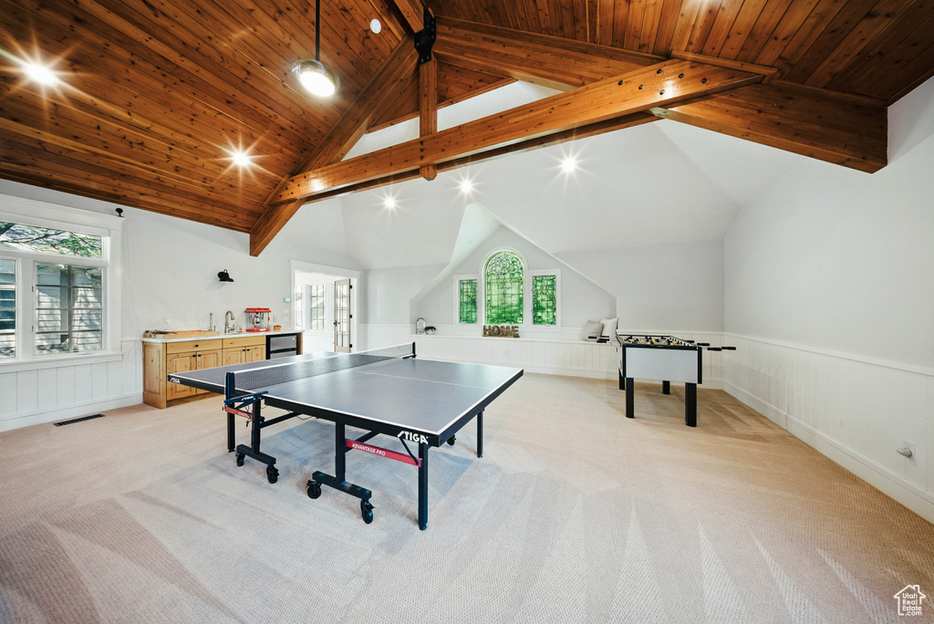 Game room with light colored carpet, a wainscoted wall, wood ceiling, and plenty of natural light