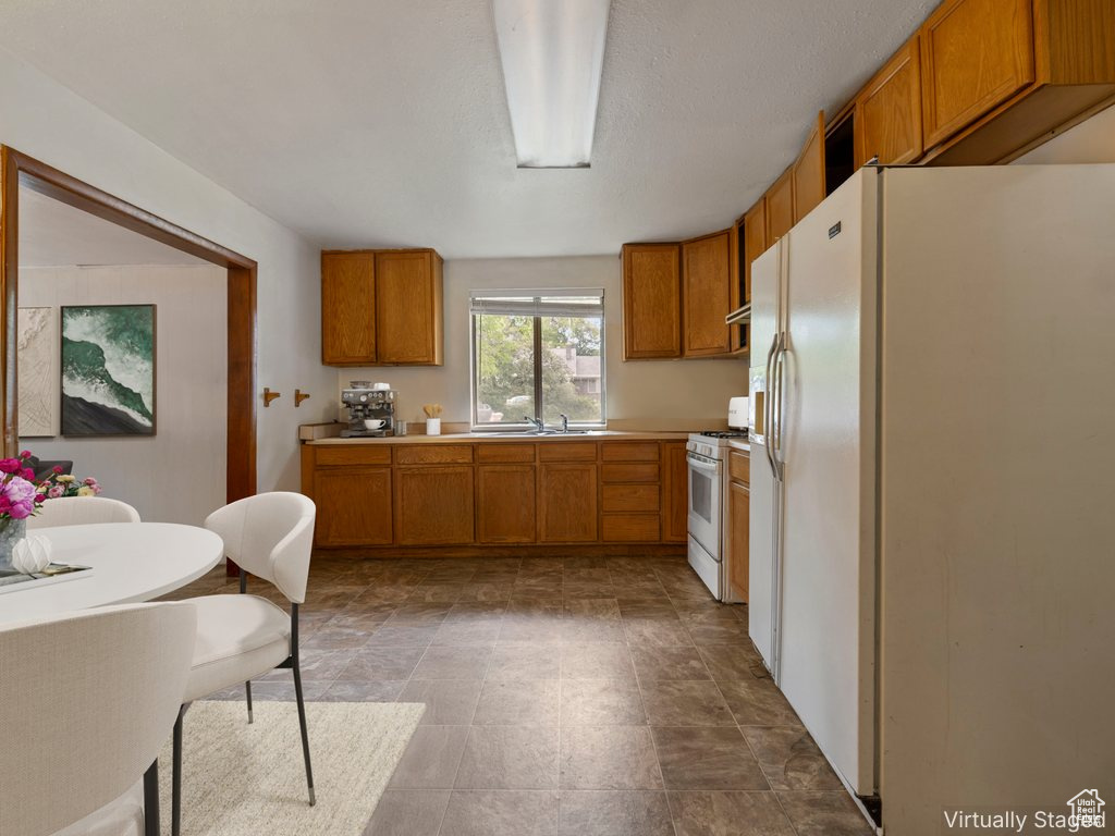 Kitchen featuring white appliances, brown cabinetry, and light countertops